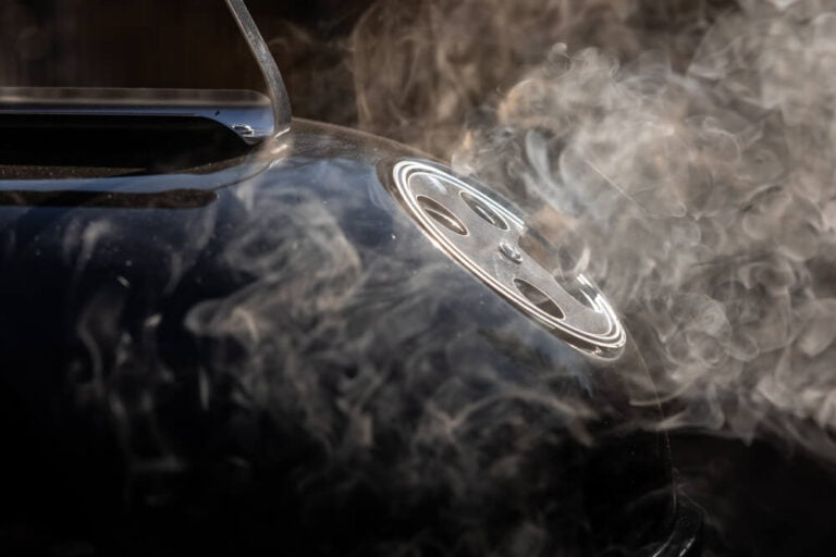 Smoke coming out from the ventilation opening of a smoker grill. Round ventilation opening in open position to allow exit of smoke fumes.